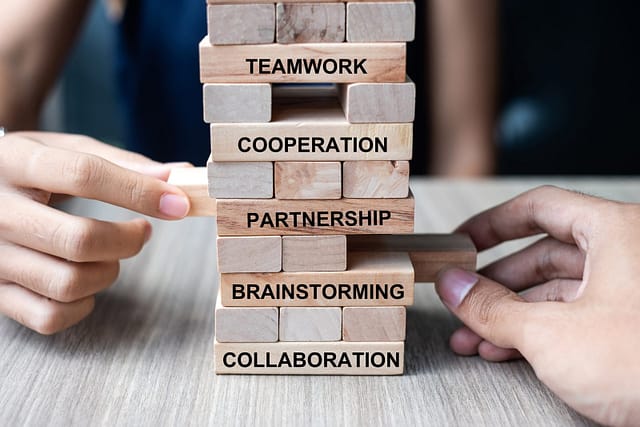 hand-pulling-block-with-text-teamwork-brainstorm-2025-03-08-02-18-31-utc Businessman and Businesswoman hand placing or pulling wooden block on the tower. Business planning, Risk Management, Solution, strategy , Partnership and Cooperation Concepts